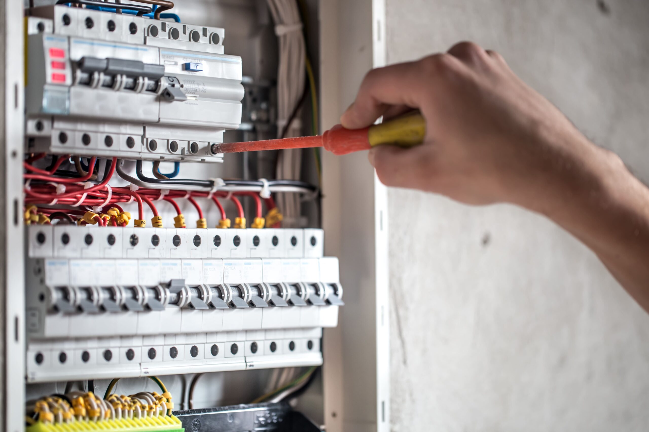 hombre un tecnico electrico que trabaja en una centralita con fusibles instalacion y conexion de equipos electricos de cerca (1)